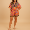 Woman wearing an orange boho summer jumpsuit with wide legs and batwing sleeves, perfect for beach days and casual summer outings.