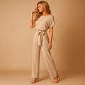 Woman wearing a glitter halter jumpsuit with an open back and flared legs, perfect for galas, parties, and festive occasions.